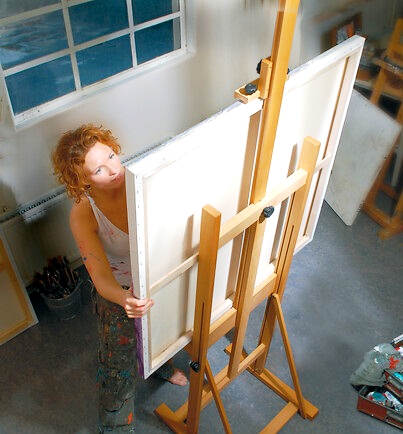 Жена работеща на голям Н-образен статив за рисуване.