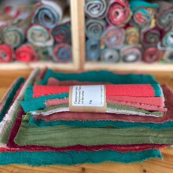 Разноцветни памучни остатъци от плат за Сашико и крафт проекти, подредени на рула върху дървена маса в ателие.